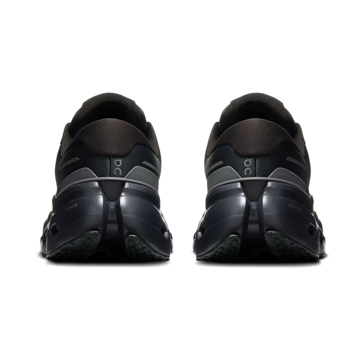 Rear view of a pair of On Women’s Cloudrunner 3 Waterproof Running Shoes in Black/Black, featuring a unique segmented sole design, displayed against a white background.