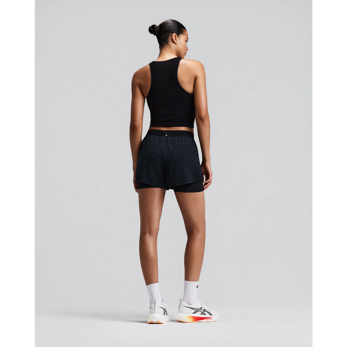 Women's Bandit CoolGrid 2-in-1 Run Short Black back full body view on female runner showing GripDot hem grip with reflective centre back branding and CoolGrid breathable construction