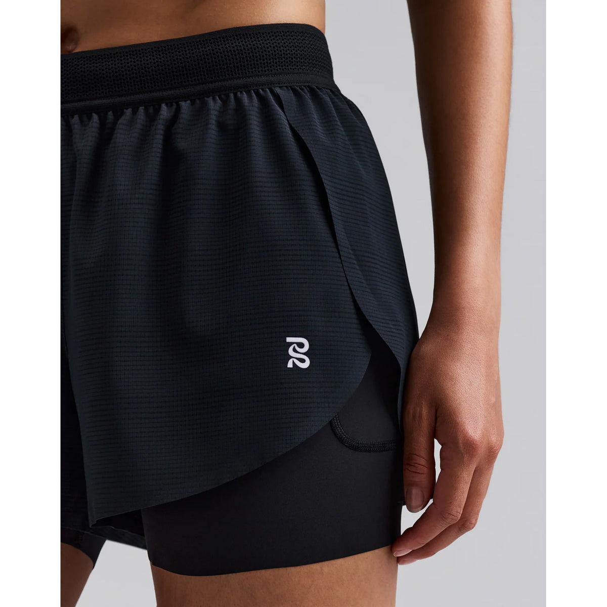 Women's Bandit CoolGrid 2-in-1 Run Short Black side view on female runner showing CoolGrid breathable outer with GripDot hems and waterproof leg pocket for comfortable running and racing