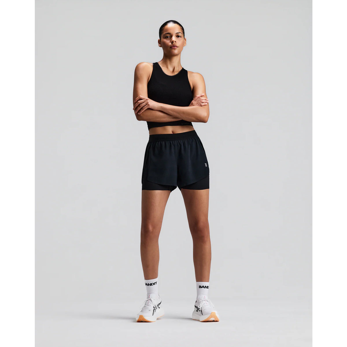 Women's Bandit CoolGrid 2-in-1 Run Short Black front full body view on female runner showing 2-in-1 CoolGrid outer with moisture-wicking liner and six-pocket system for road running and racing