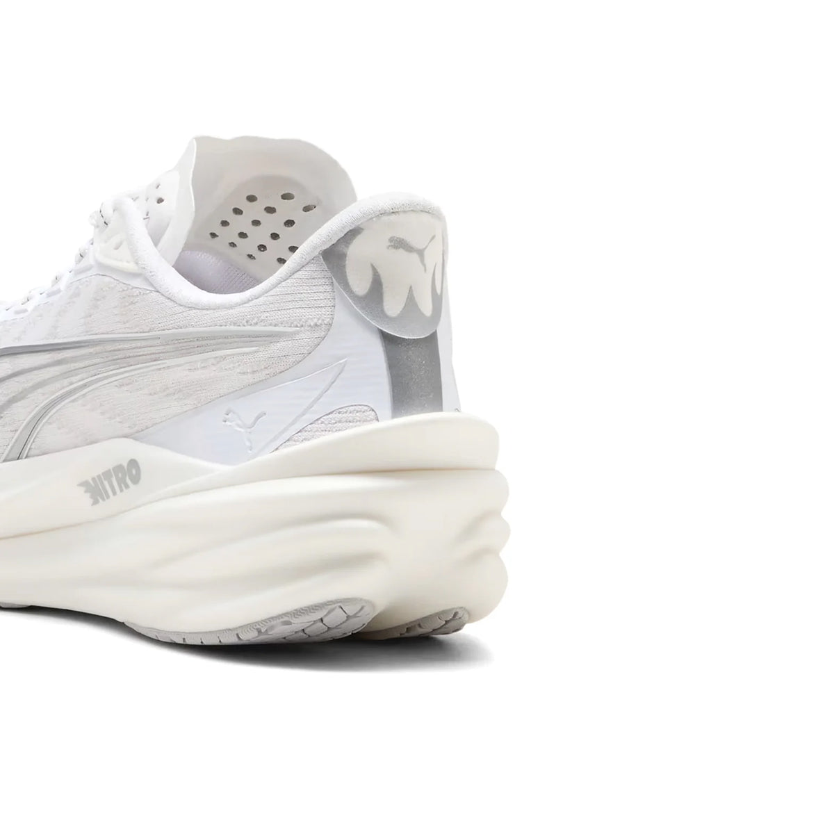 Close-up of the heel of a Women’s Deviate NITRO 4 Running Shoe in Puma White and Feather Grey, showcasing a chunky, layered sole and subtle grey accents. The heel tab displays a dripping paint design, while the iconic Puma logo is discreetly featured. This Puma model stands out among lightweight running shoes, seamlessly blending modern style with advanced performance features.