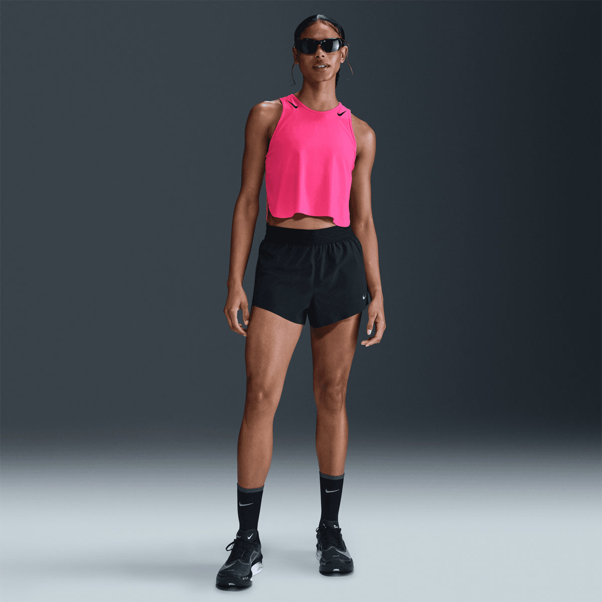 Nike AeroSwift women's Dri-FIT ADV cropped running tank in Hyper Pink / Black — full body front view worn on model showing hyper pink cropped design, black detailing and side slits for movement freedom