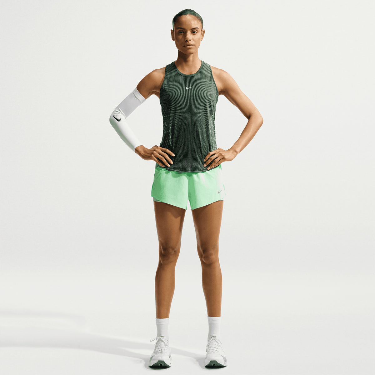 Women's Nike Dri-FIT Aeroswift Running Tank Black Light Green Spark Reflective Silver front full body view on female runner showing lightweight Aero-FIT construction with curved hem for peak breathability during warm weather running