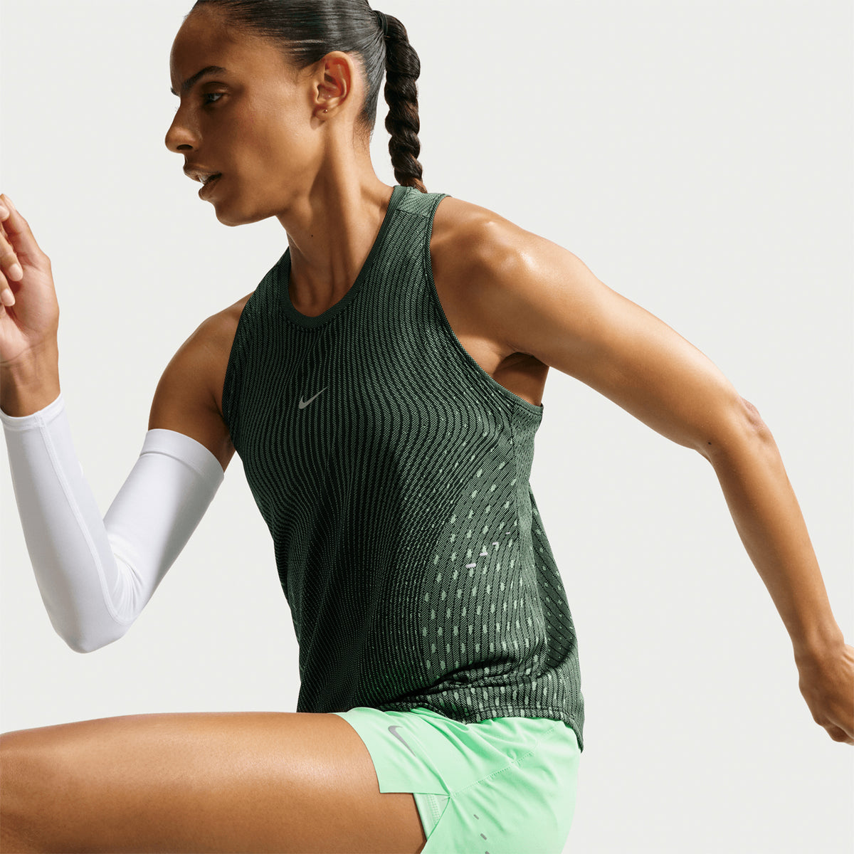 Women's Nike Dri-FIT Aeroswift Running Tank Black Light Green Spark Reflective Silver side view on female runner showing lightweight Aero-FIT construction with curved hem for coverage and unrestricted stride freedom during running