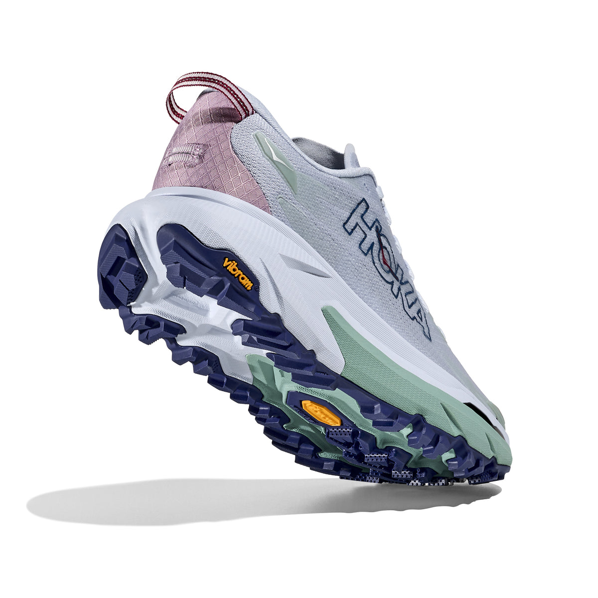 A light grey Hoka running shoe with a pale green midsole, purple outsole, and pink heel detail, shown from a rear side angle against a white background.