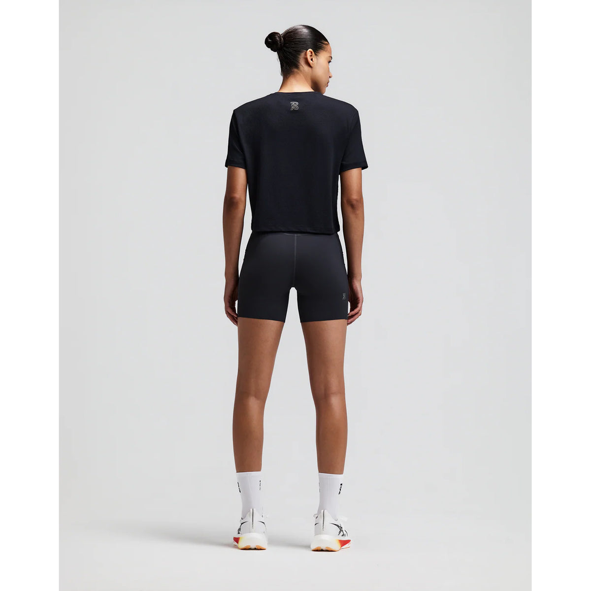 Women's Bandit Micromesh Cropped Run Tee Black back full body view on female runner showing relaxed boxy cropped fit with fast-drying Micromesh construction for comfortable running and training