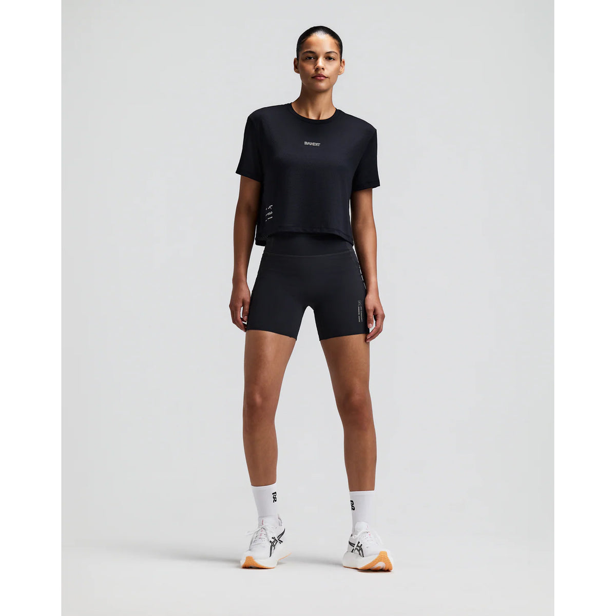 Women's Bandit Micromesh Cropped Run Tee Black front full body view on female runner showing relaxed boxy cropped silhouette with crew neckline and breathable Micromesh moisture-wicking for training and everyday running