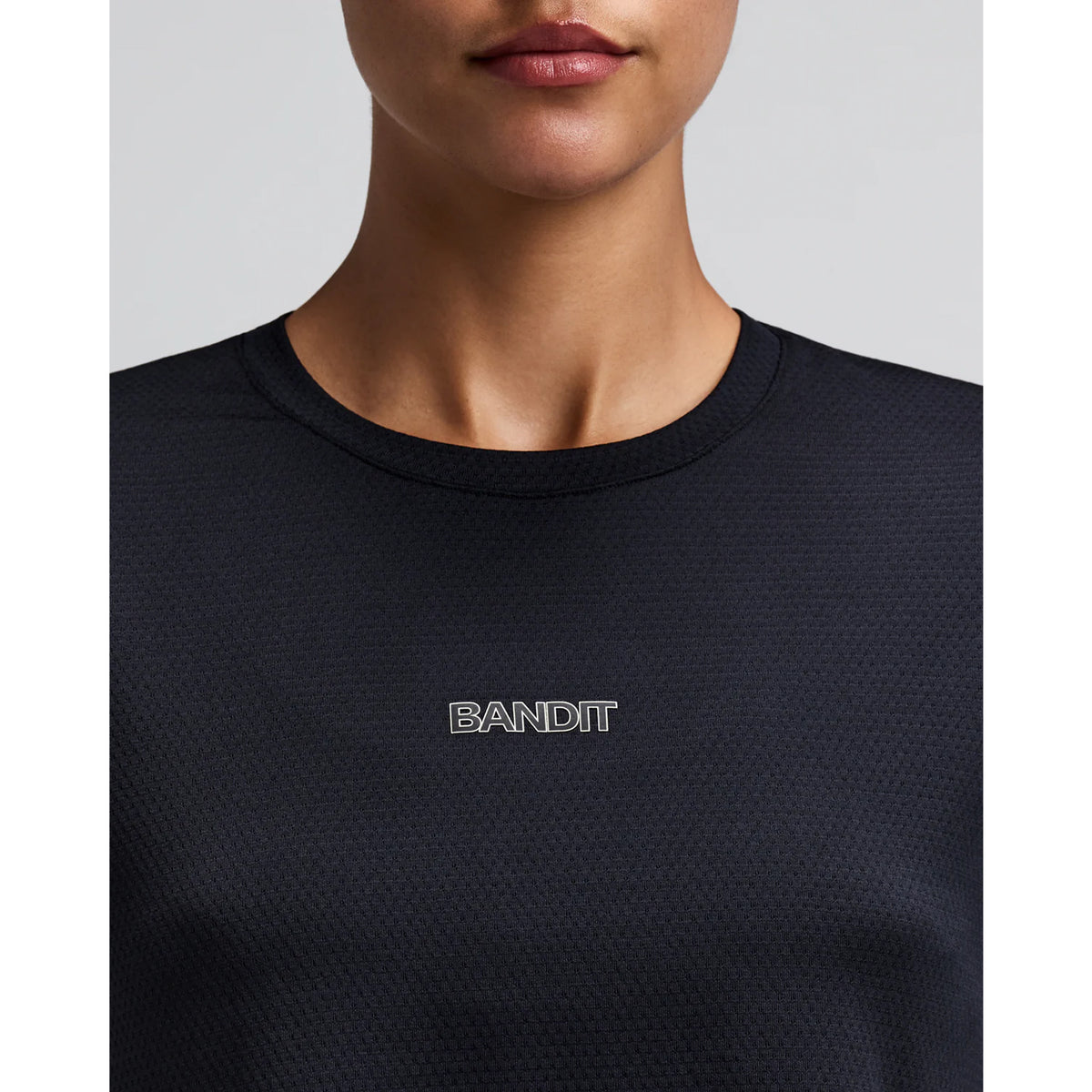 Women's Bandit Micromesh Cropped Run Tee Black close-up of front showing subtle two-tone Bandit logo branding with ultra-breathable Micromesh fabric and Oeko-Tex certified BPA-free construction