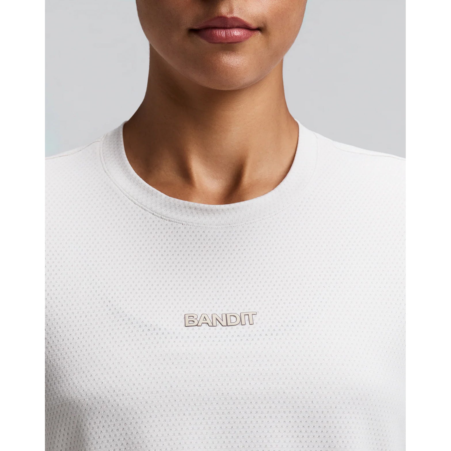 Women's Bandit Micromesh Cropped Run Tee Plaster close-up of front showing subtle two-tone Bandit logo branding with ultra-breathable Micromesh fabric and Oeko-Tex certified BPA-free construction