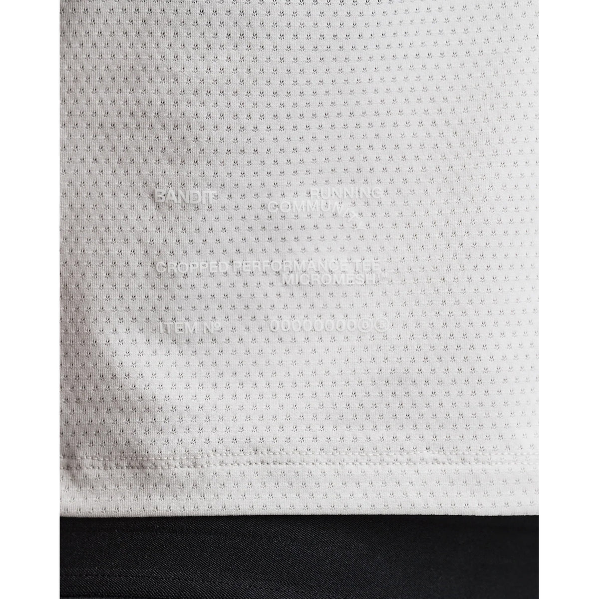 Women's Bandit Micromesh Cropped Run Tee Plaster close-up of hem showing subtle two-tone Bandit logo with reflective details for low-light visibility during running
