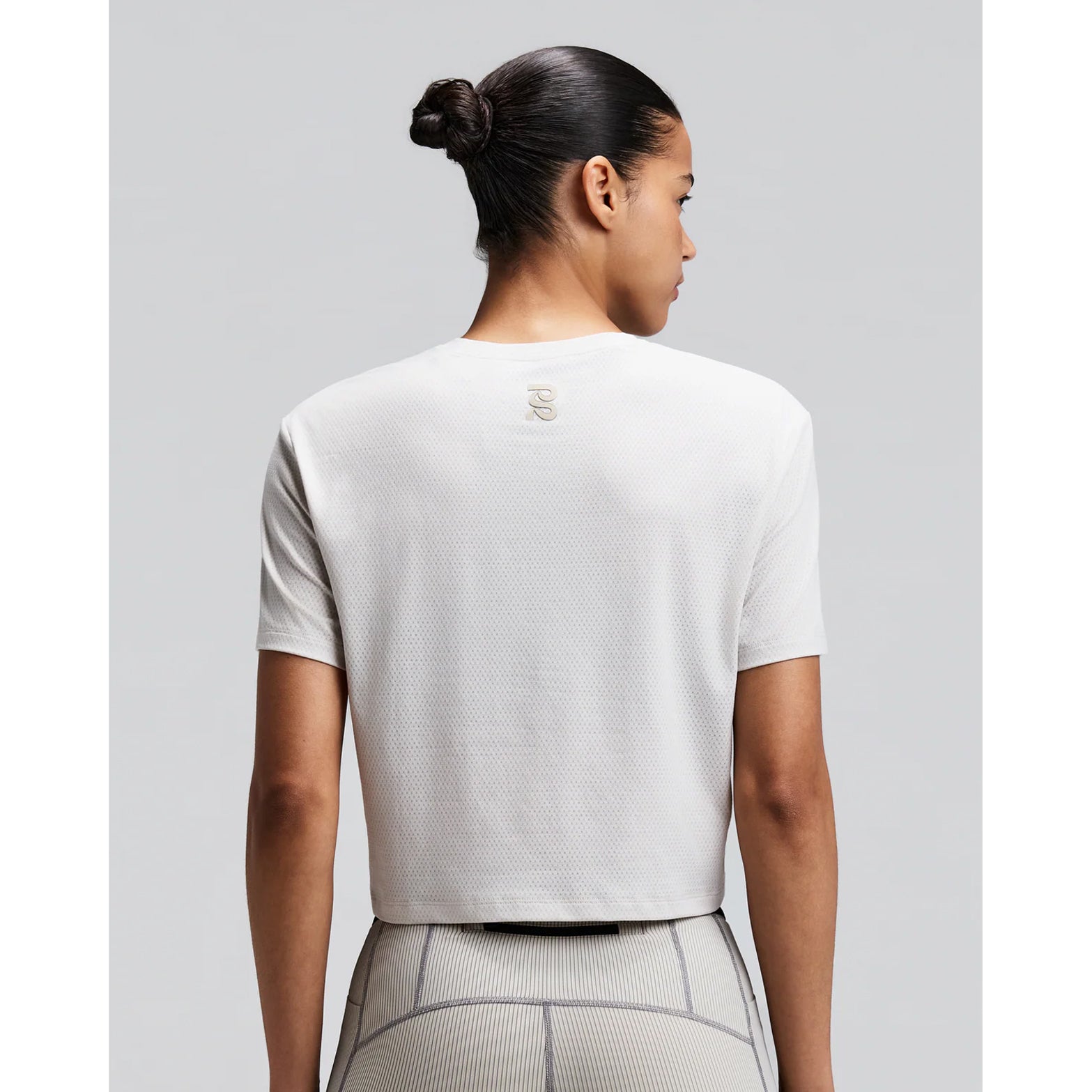 Women's Bandit Micromesh Cropped Run Tee Plaster back view on female runner showing breathable Micromesh construction with fast-drying sweat-wicking fabric for comfortable running