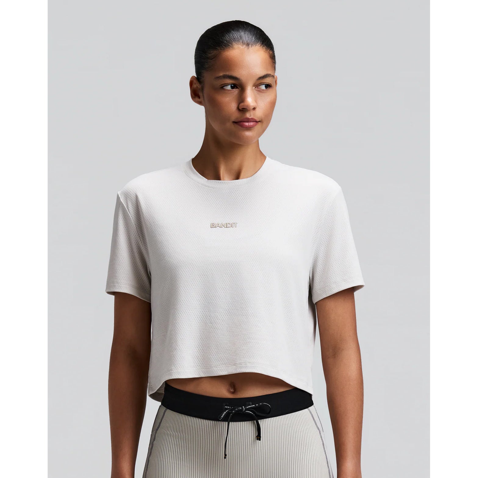 Women's Bandit Micromesh Cropped Run Tee Plaster front view on female runner showing boxy cropped fit with crew neckline and breathable Micromesh construction for running and training