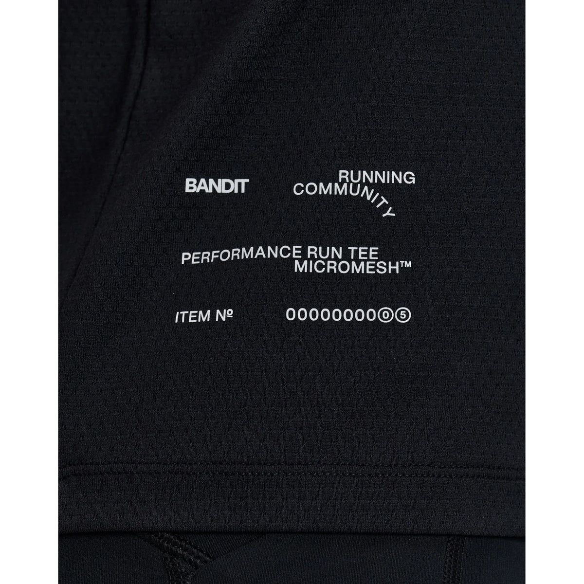 Bandit Micromesh Run Tee women's in Black — closeup showing reflective infographic detail at front hem on Micromesh™ breathable fabric construction