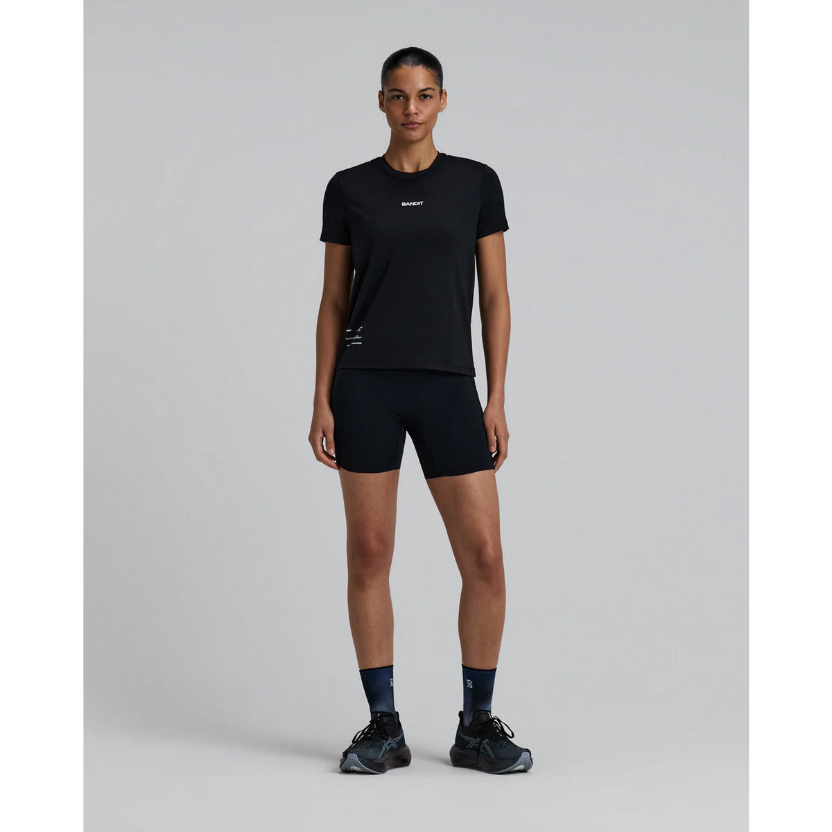 Bandit Micromesh Run Tee women's in Black — full body front view worn on model showing relaxed fit silhouette, Micromesh™ fabric drape and dyed-to-match reflective graphic at centre front
