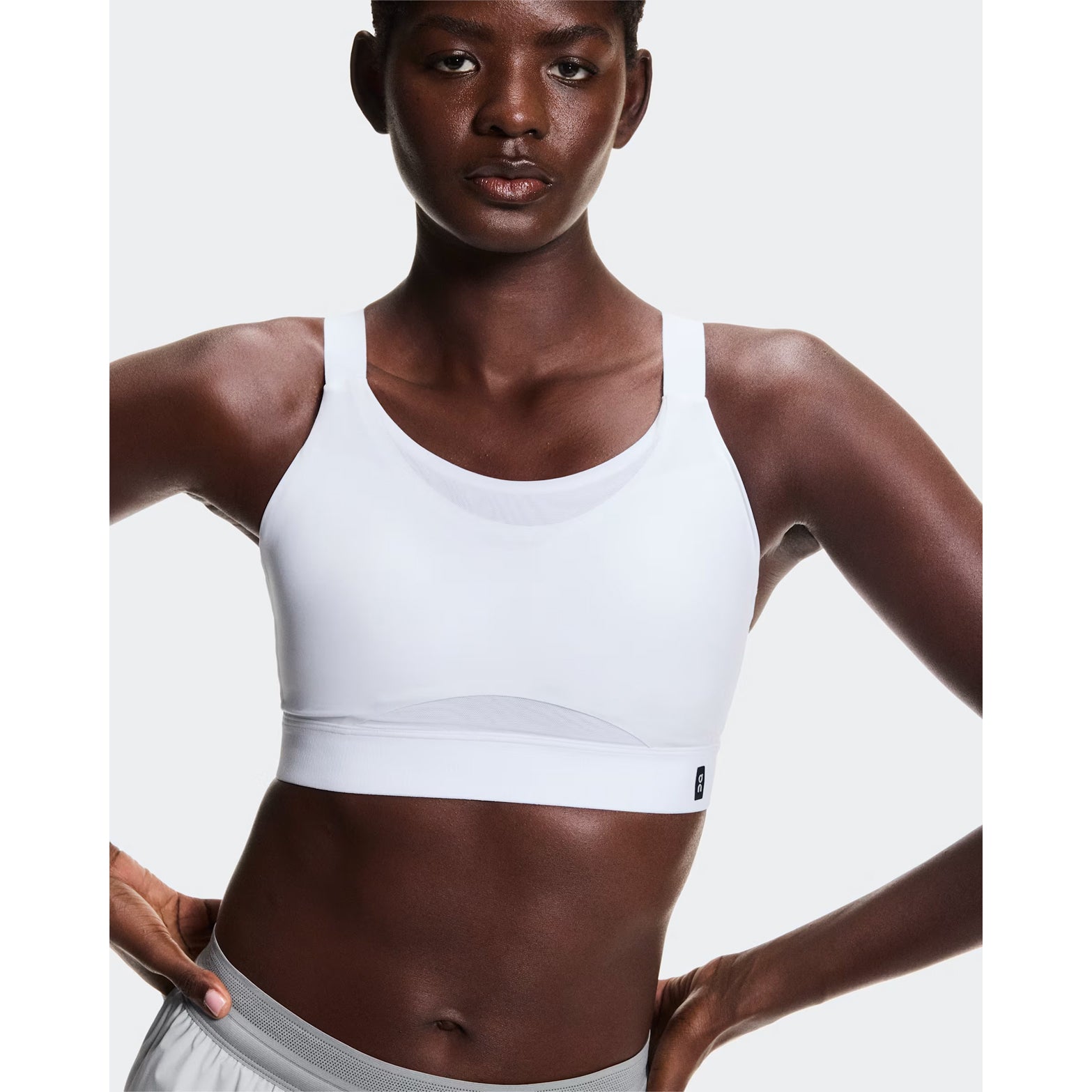Women's On Performance Bra White front view on female runner showing pull-on design with smooth four-way stretch material and adjustable straps