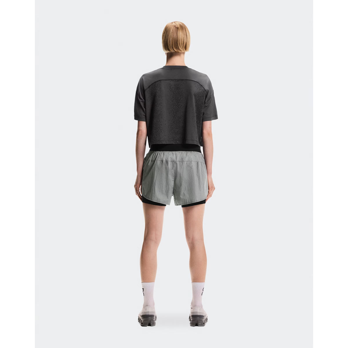 Women's On Performance Volt Shorts Glacier full body back view on female runner showing additional back pocket storage and water-repellent iridescent outer layer