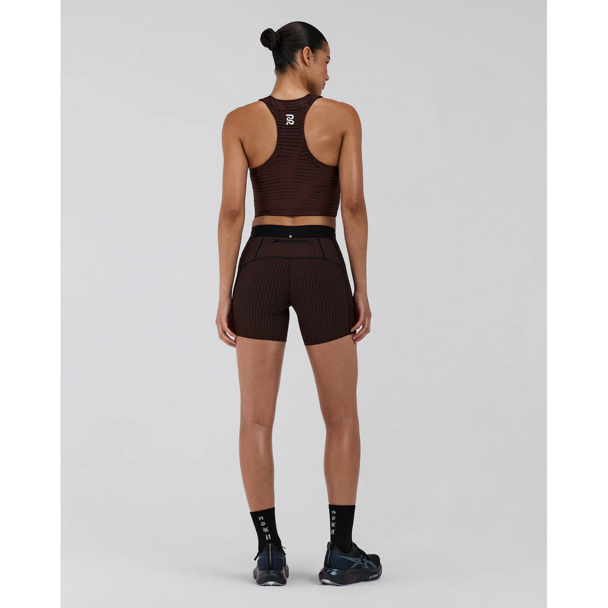Women's Bandit Stamina Race Crop Organic Stripe Cacao full body back view on female runner showing zero-chafe construction with gel pocket system and embossed branding
