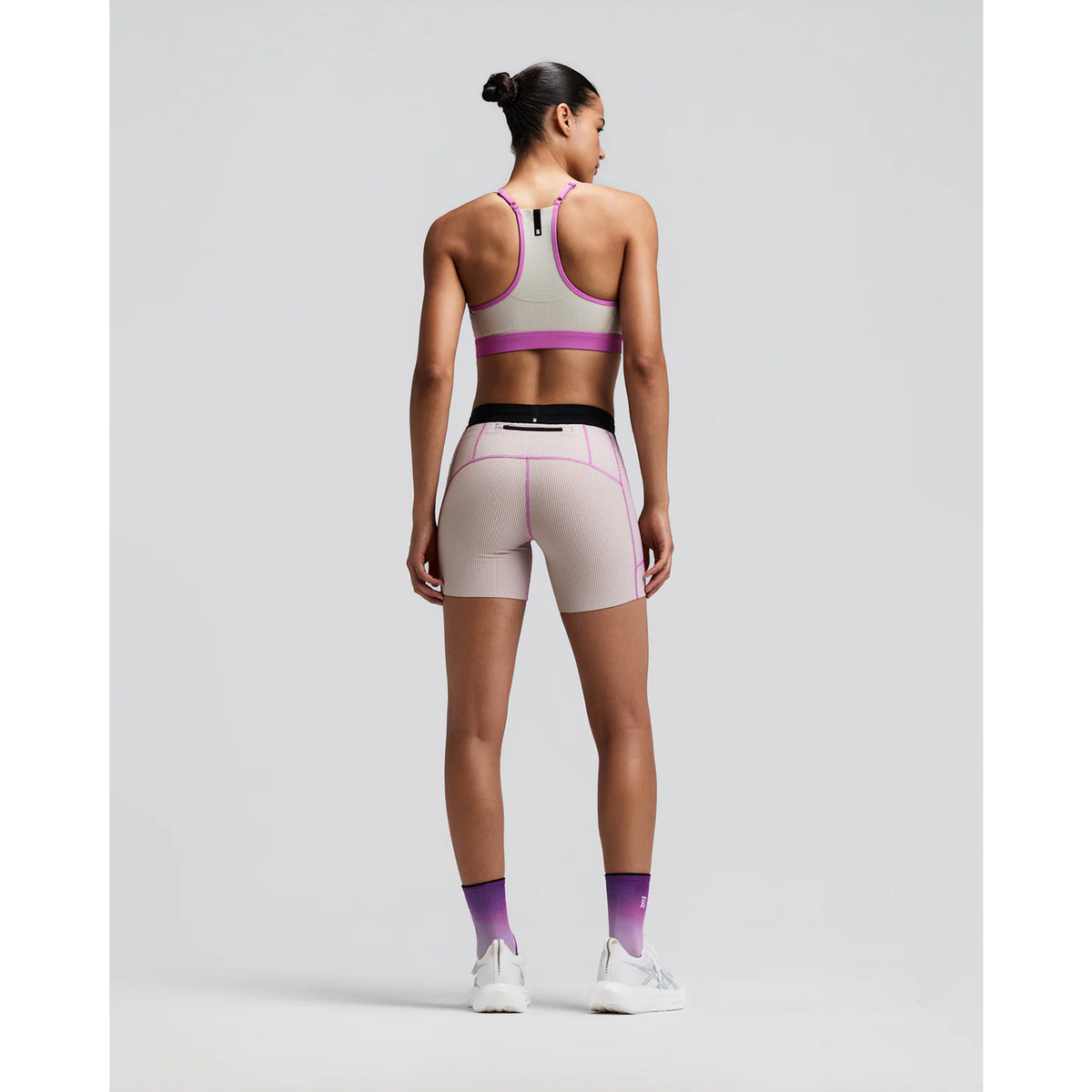 Women's Bandit Striped Cadence 5 Inch Compression Shorts Plaster Orchid back full body view on female runner showing grip tape hems with back zipper pocket and ultra-compressive Striped Cadence construction for long-distance running