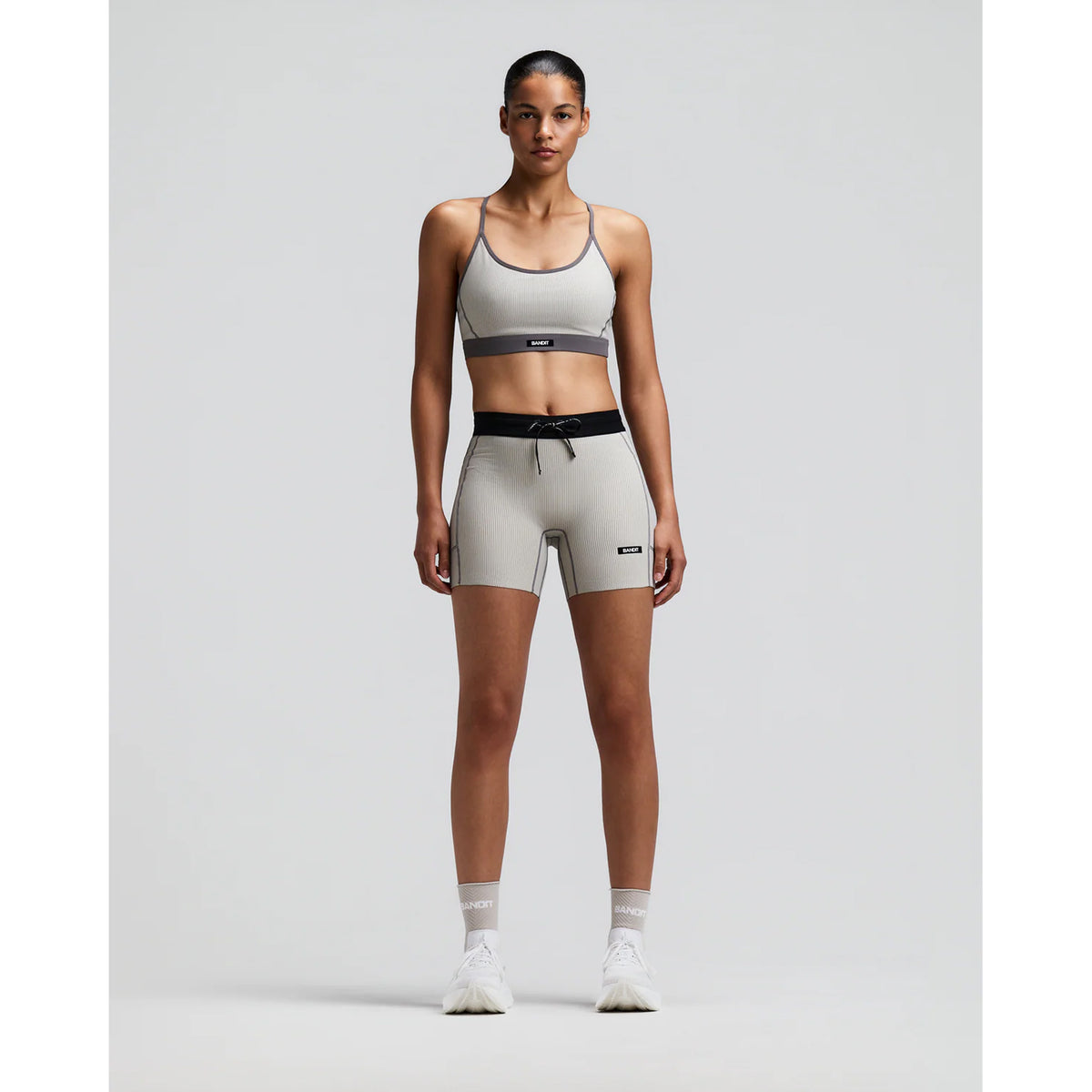 Women's Bandit Striped Cadence 5 Inch Compression Shorts Plaster Slate front full body view on female runner showing 5-inch inseam with ultra-compressive ribbed knit and five-pocket storage system for racing and marathon training