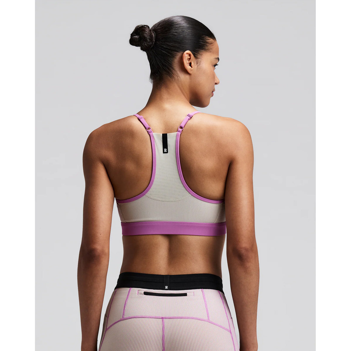 Women's Bandit Striped Cadence Strappy Bra Plaster Orchid back view on female runner showing Powermesh back panel with waterproof centre back phone pocket and reflective details for low-light visibility