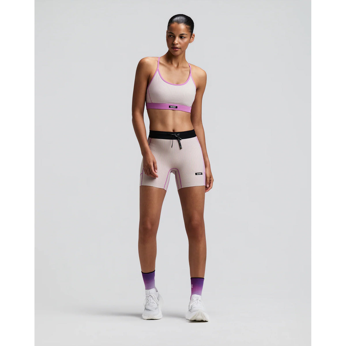 Women's Bandit Striped Cadence Strappy Bra Plaster Orchid front full body view on female runner showing adjustable straps with Striped Cadence ribbed compression and three-pocket system for road running and racing