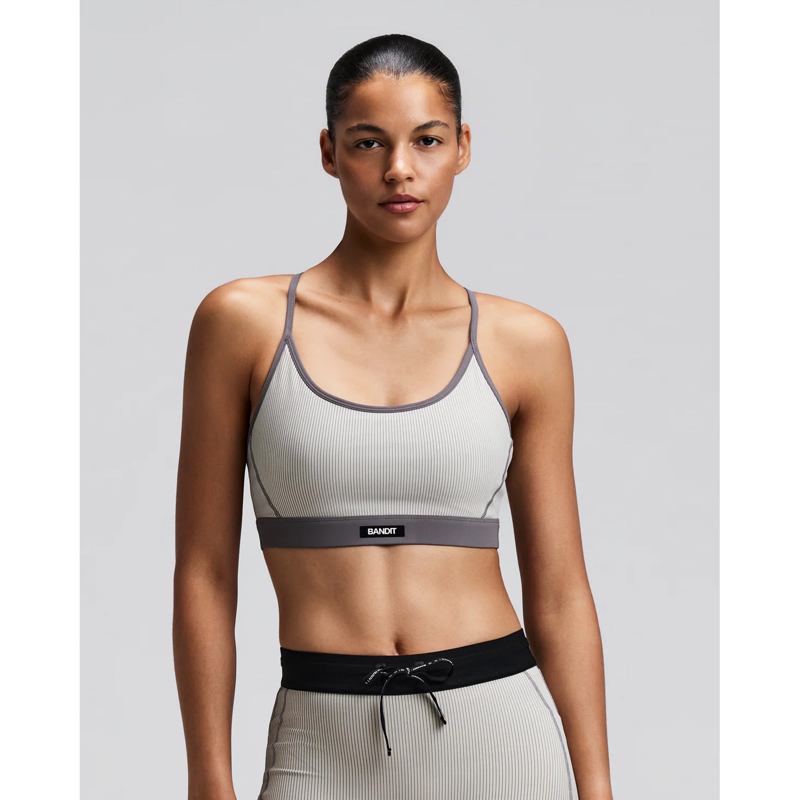 Women's Bandit Striped Cadence Strappy Bra Plaster Slate front view on female runner showing adjustable straps with Striped Cadence ribbed compression and Vanisher band at hem for race day performance