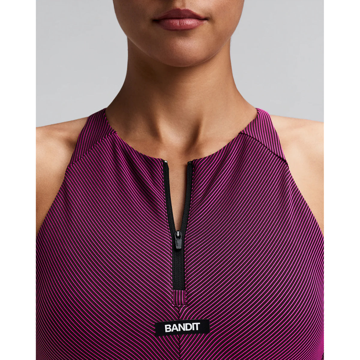 Women's Bandit Striped Cadence Zip Front Race Crop Espresso Azalea close-up of front showing custom-branded zip with Striped Cadence ribbed compression and silicone front patch detail