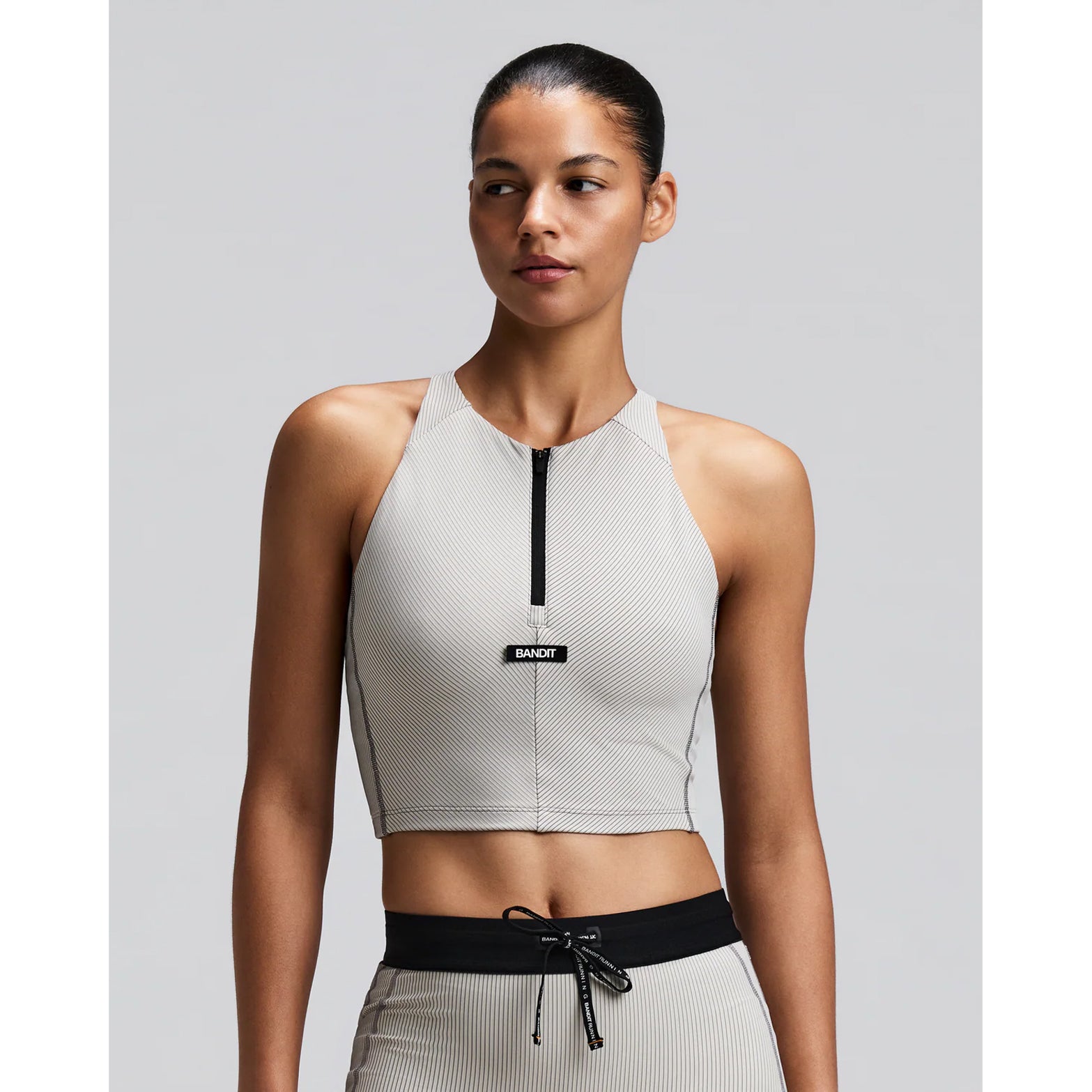 Women's Bandit Striped Cadence Zip Front Race Crop Plaster Slate front view on female runner showing halter fit with custom-branded zip front and Striped Cadence ribbed compression for race day performance