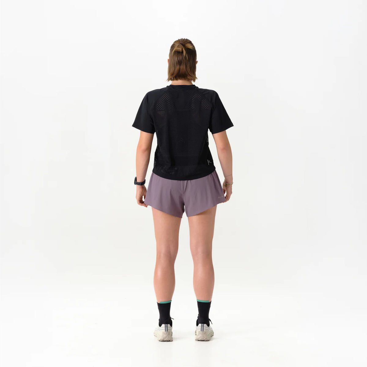 Women's Raide Thermal Dispersion Tee Black back full body view on female runner showing body-mapped centre back perforations with reflective branding and Italian-knit microfibre for evaporative cooling during road running