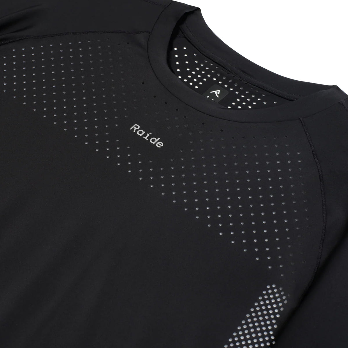 Women's Raide Thermal Dispersion Tee Black close-up of front showing reflective Raide branding with body-mapped laser-cut perforations and cool-to-touch 115gsm Italian-knit microfibre construction