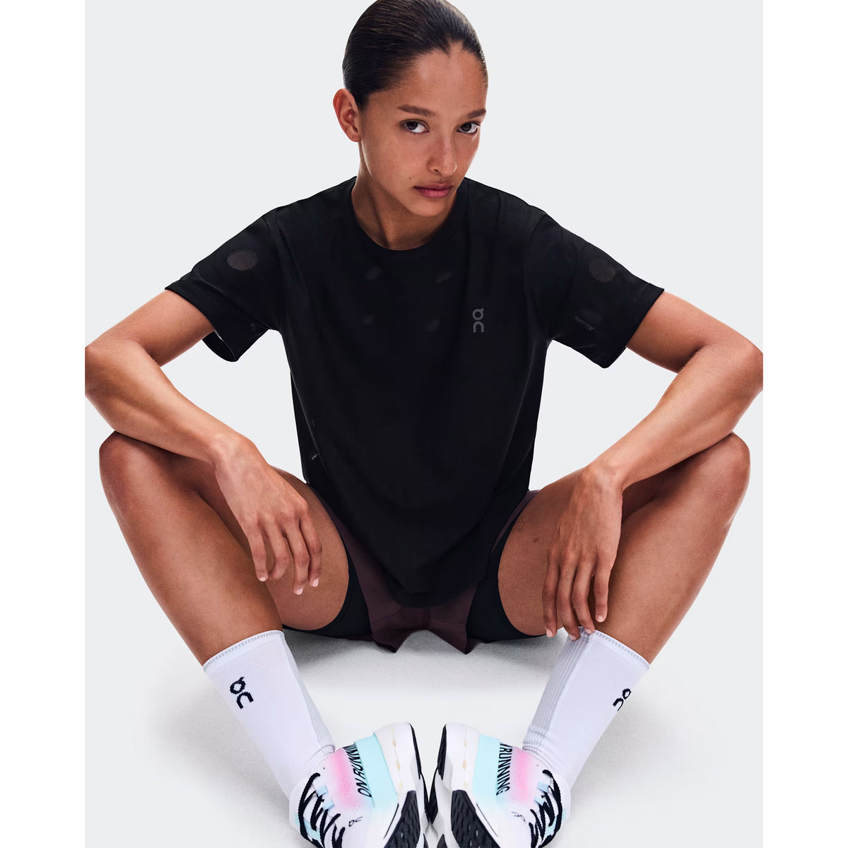 Women's On Zero-T Breathe Black front view on female runner sitting showing ultralight functional jacquard construction with On DryTec breathable fabric and minimalist distraction-free fit