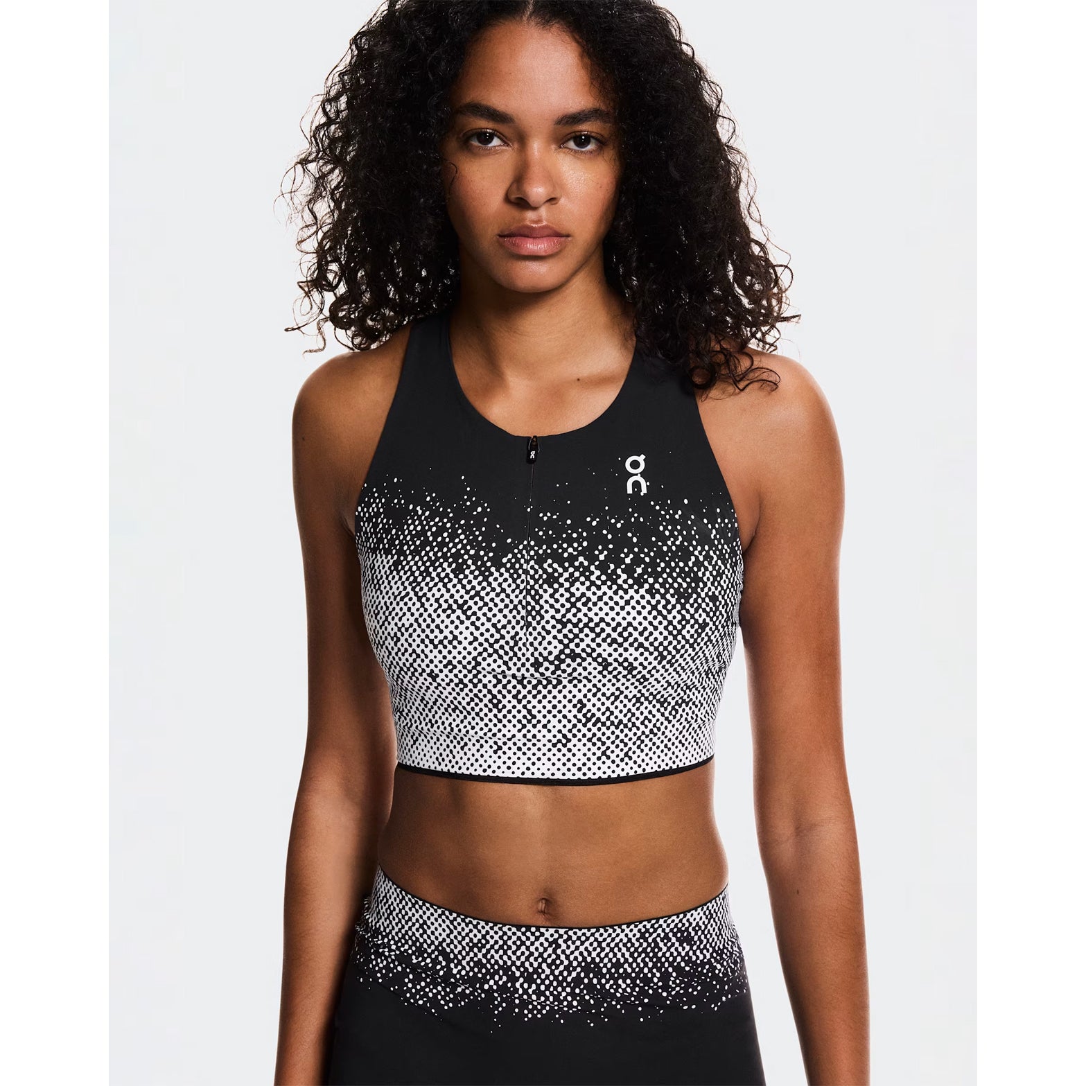 Women's On Zero Crop White Black front view on female runner showing lightweight moisture-wicking fabric with zip front for adjustable coverage and ventilation