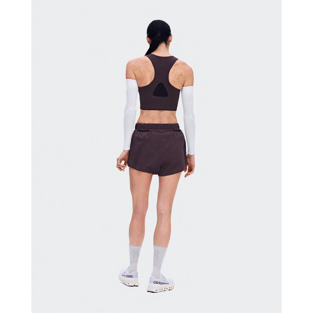 Women's On Zero Shorts Urchin back full body view on female runner showing zip pocket and gel storage with perforated ventilation outer for practical comfortable race day performance