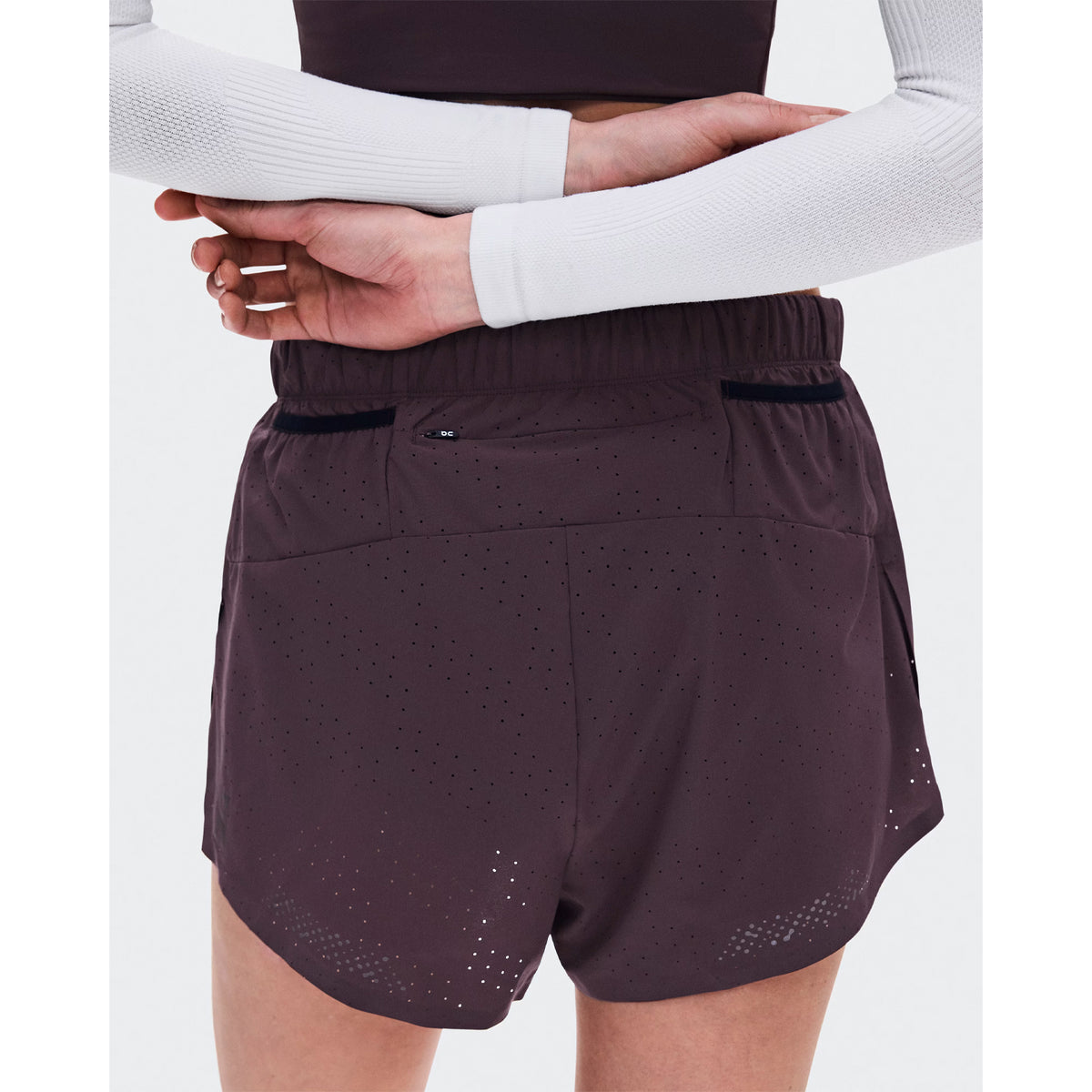 Women's On Zero Shorts Urchin back view on female runner showing zip pocket and two gel mesh pockets with perforated ventilation construction for race day storage and airflow