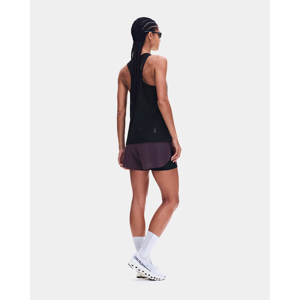 Women's On Zero Tank Breathe Black back full body view on female runner showing athletic racerback design with functional jacquard ventilation and signature reflective detailing for high-paced running