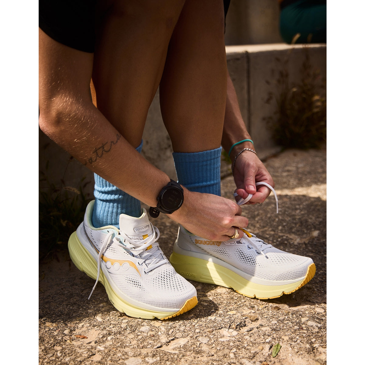 Saucony Guide 19 Wide Fit women's running shoe — side view worn on model showing black flexible mesh upper, CenterPath Technology sidewall profile and silver PWRRUN cushioning midsole stack