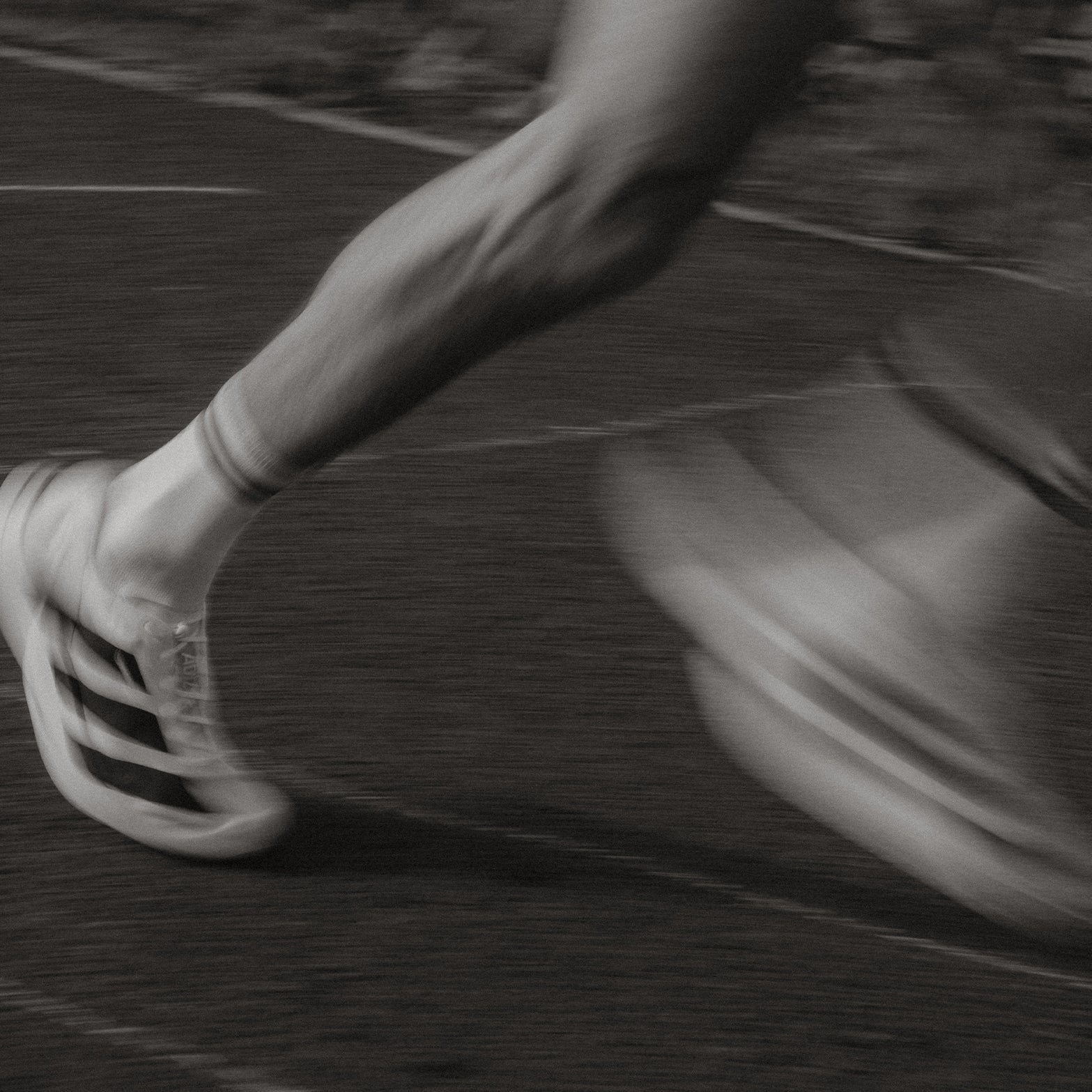 Black and white motion blur close-up of runner's feet and running shoes during running event