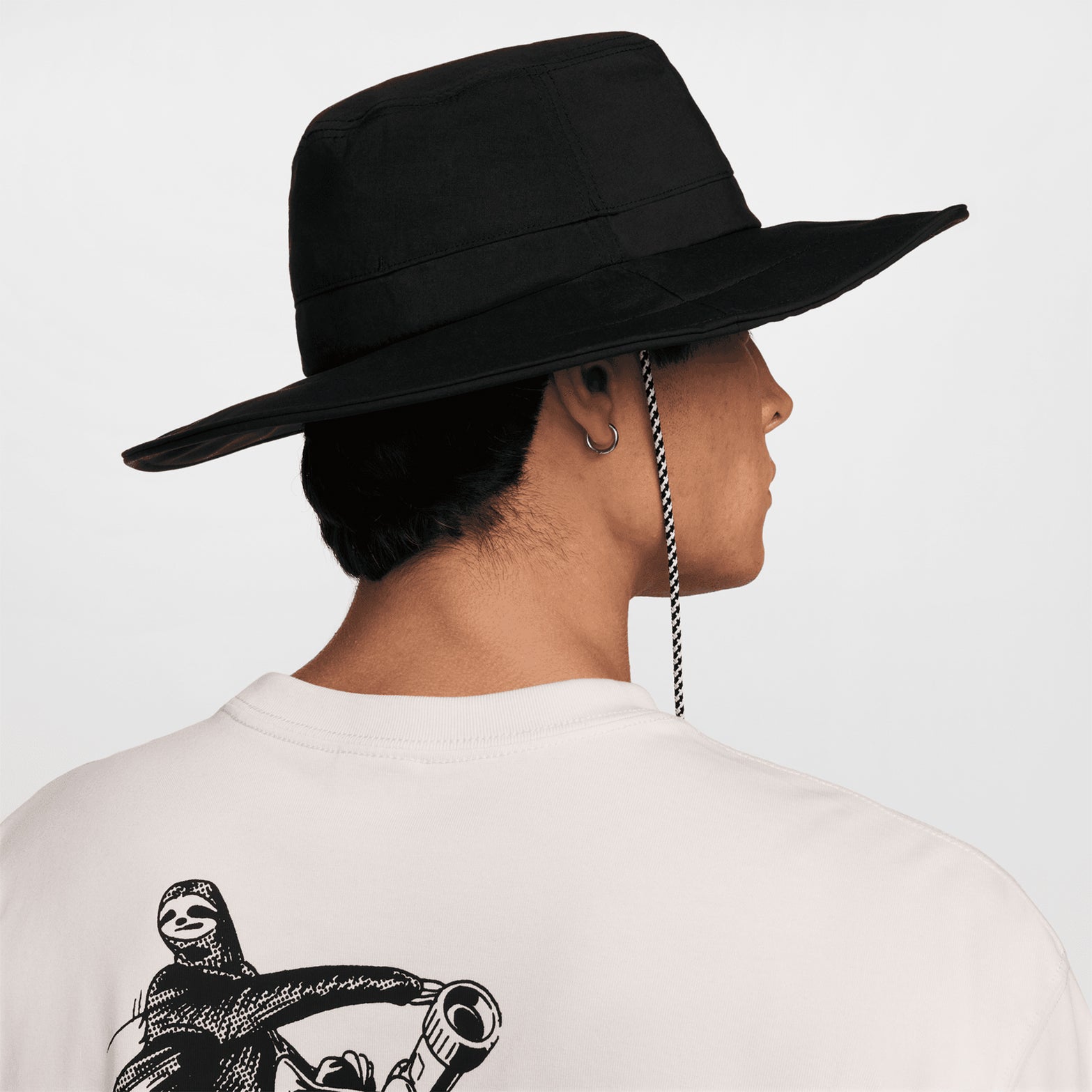 Nike ACG Apex bucket hat in Black — back view worn on male model showing black nylon taffeta construction, adjustable strap detail and Dri-FIT sweatband