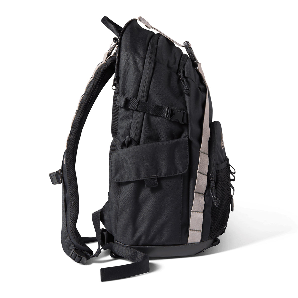 Nike ACG Daymax 25L Backpack in Black with College Grey accents, featuring a side pocket, mesh water bottle holder, and padded shoulder straps. This adventure backpack is shown standing upright on a white background, viewed from the side.