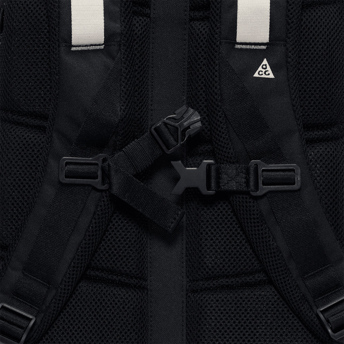 Close-up of the Nike ACG Daymax 25L Backpack in Black / College Grey, showcasing mesh padding, adjustable straps with a plastic buckle, and a small white triangle ACG logo on one strap—an adventure-ready backpack engineered for comfort and durability.