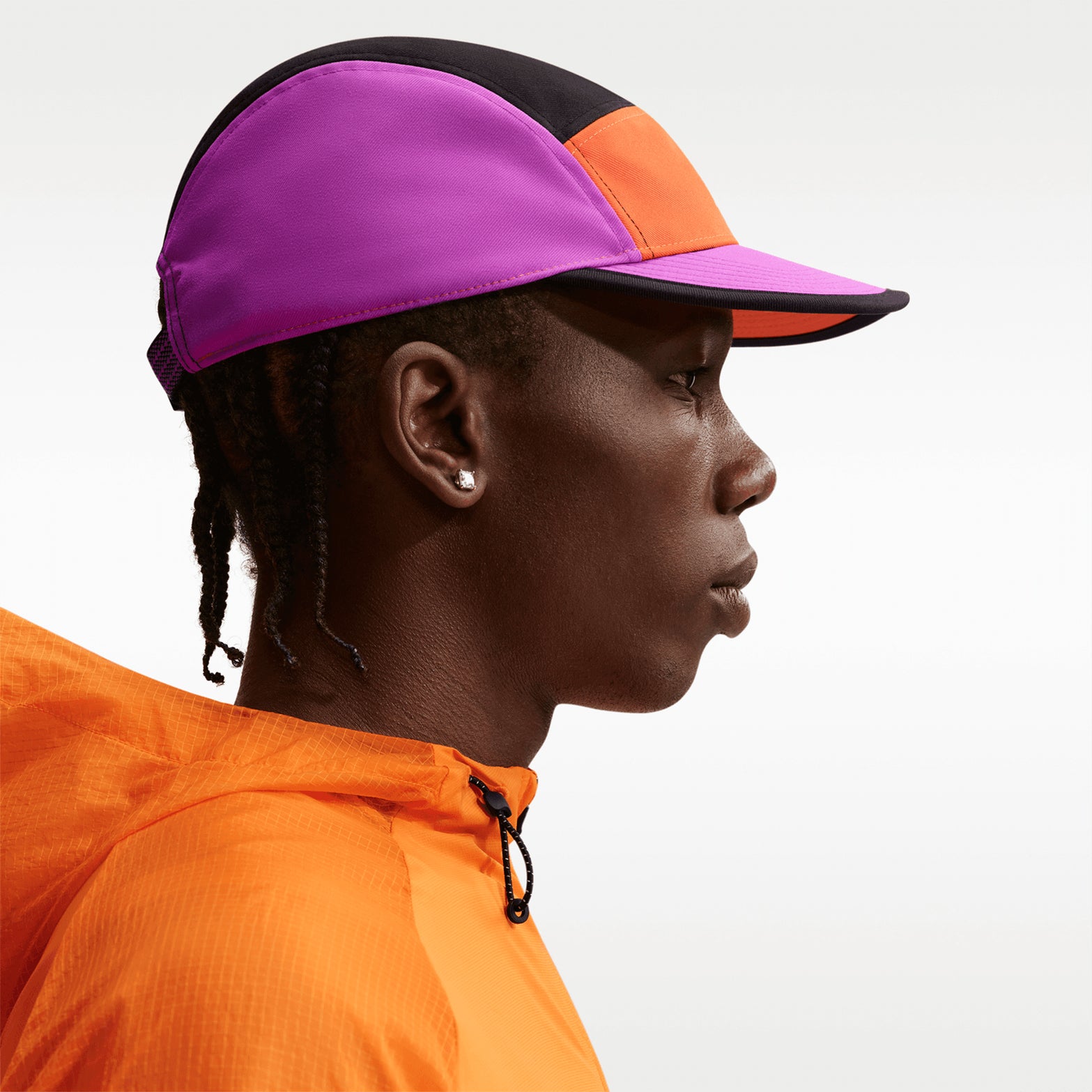 Nike ACG Fly Unstructured Cap Safety Orange Vivid Purple Black side view on model showing snug athletic fit with low depth and water-repellent construction