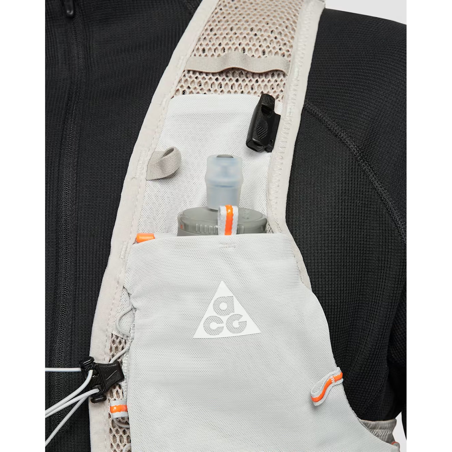 Nike ACG Goat Pack 5L Vest in Grey Fog / Safety Orange / Summit White — closeup showing front hydration flask storage pocket with grey fog DyneemaⓇ mesh base and safety orange accent detailing for 600ml flask carry