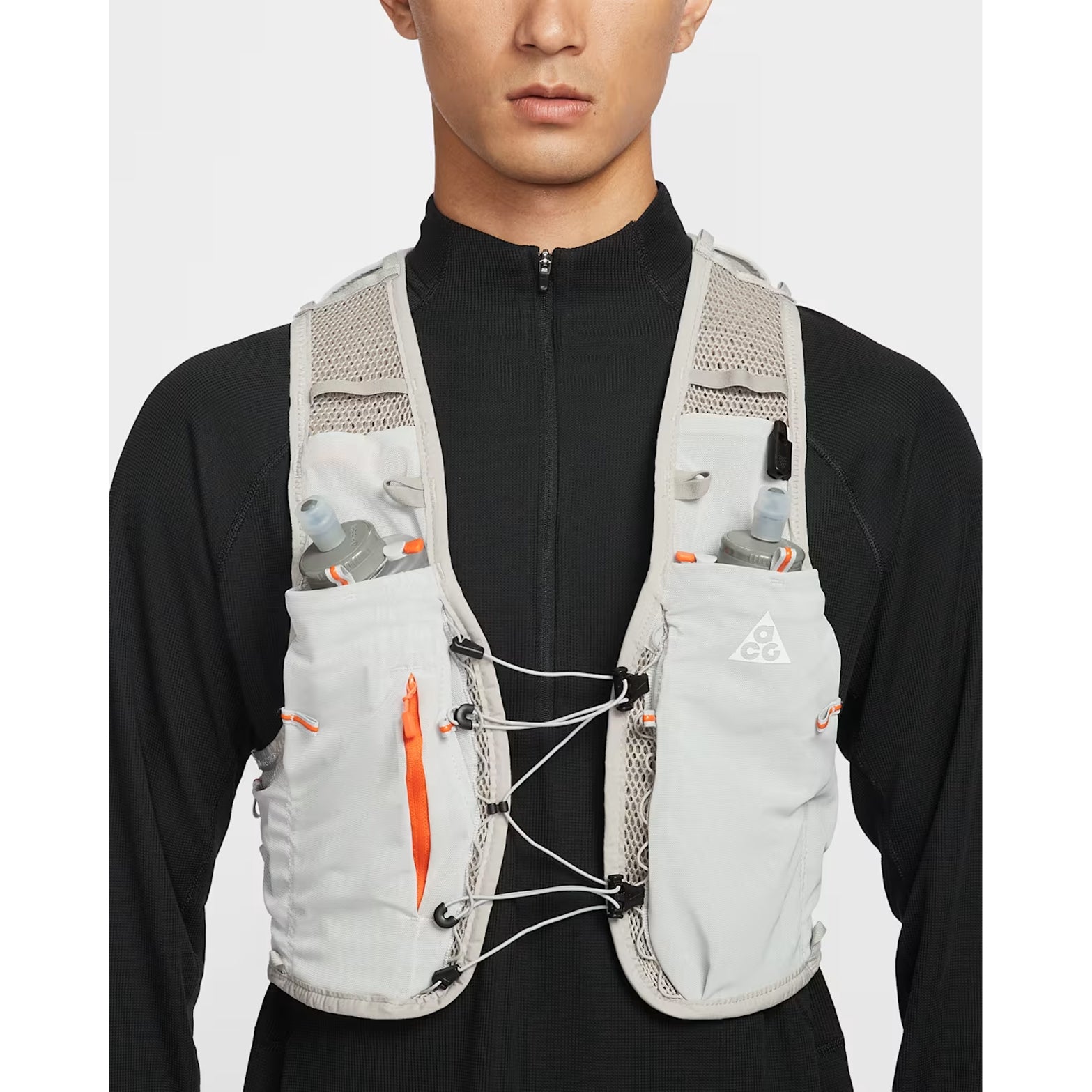 Nike ACG Goat Pack 5L Vest in Grey Fog / Safety Orange / Summit White — closeup showing chest tension system detail, zipped phone storage pocket and integrated whistle on grey fog DotAir body fabric with safety orange accents