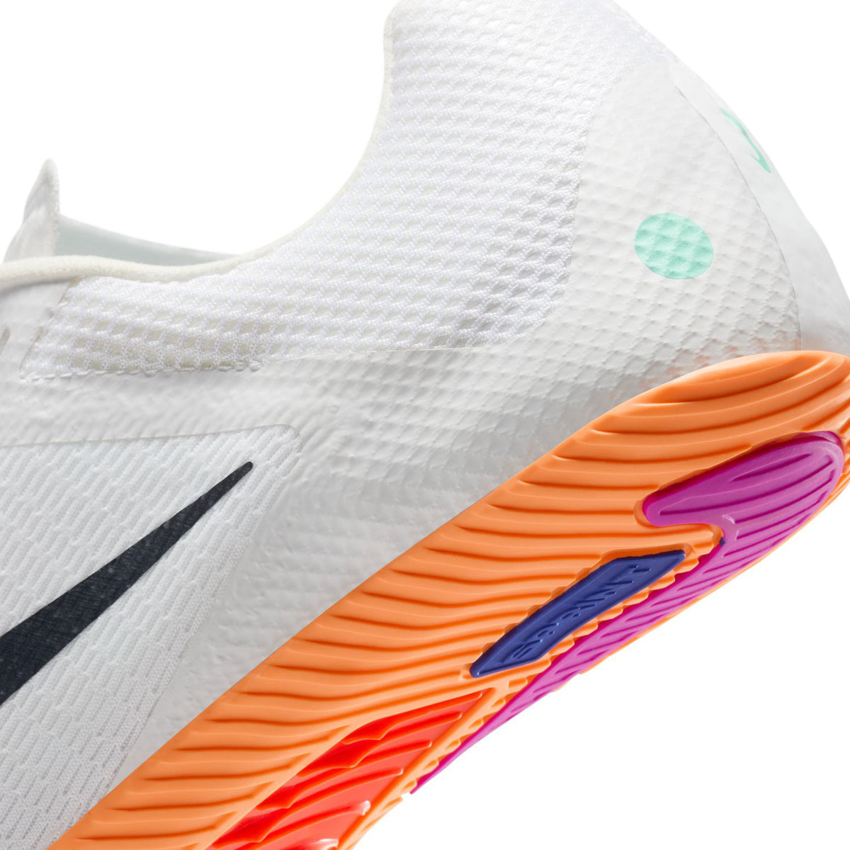 Close-up of a white athletic sneaker featuring a textured upper, black Nike swoosh, and an orange sole with pink and purple accents. Mint green dots are visible on the heel.