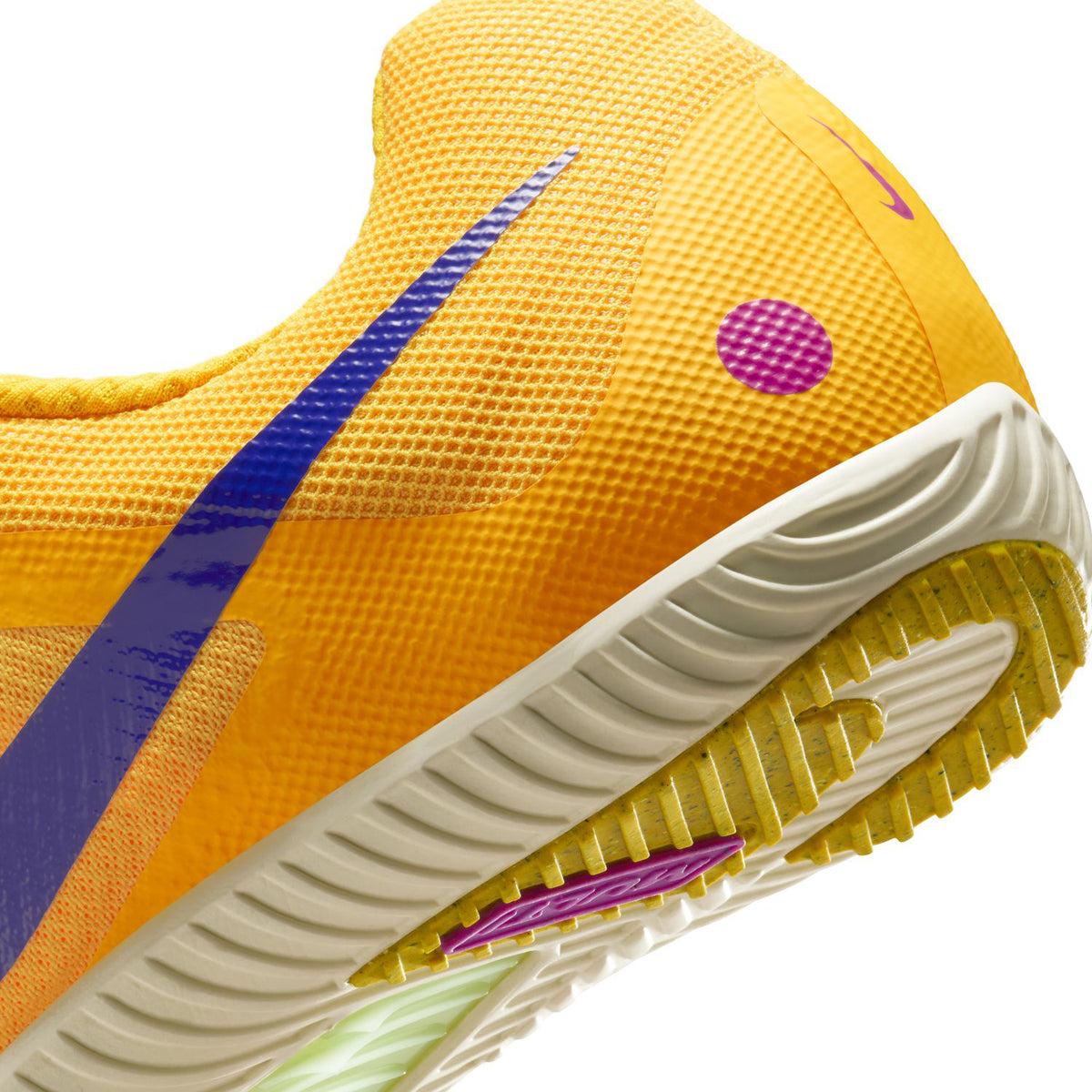 Close-up of the heel and sole of a yellow athletic shoe with a purple swoosh, pink dot detail, and textured white outsole featuring yellow and pink accents.