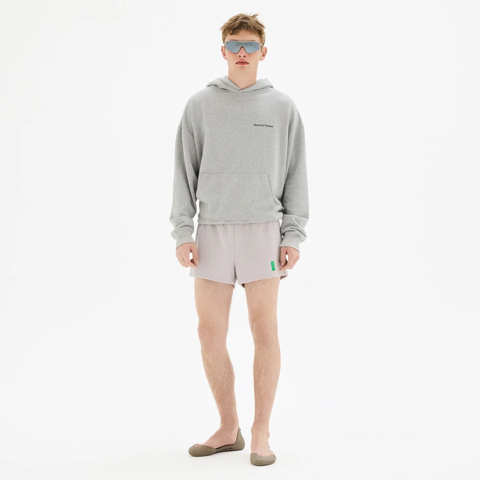 District Vision California Cotton Hoodie in Runners Heather Grey — front view worn on model showing slightly cropped boxy fit, front pocket, Runners graphic and heather grey pigment dye stone wash cotton drape