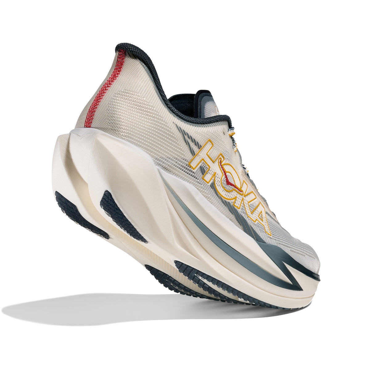 A light grey HOKA running shoe with a thick, sculpted white sole, yellow HOKA logo, navy and red accents, and a mesh upper, photographed against a white background.