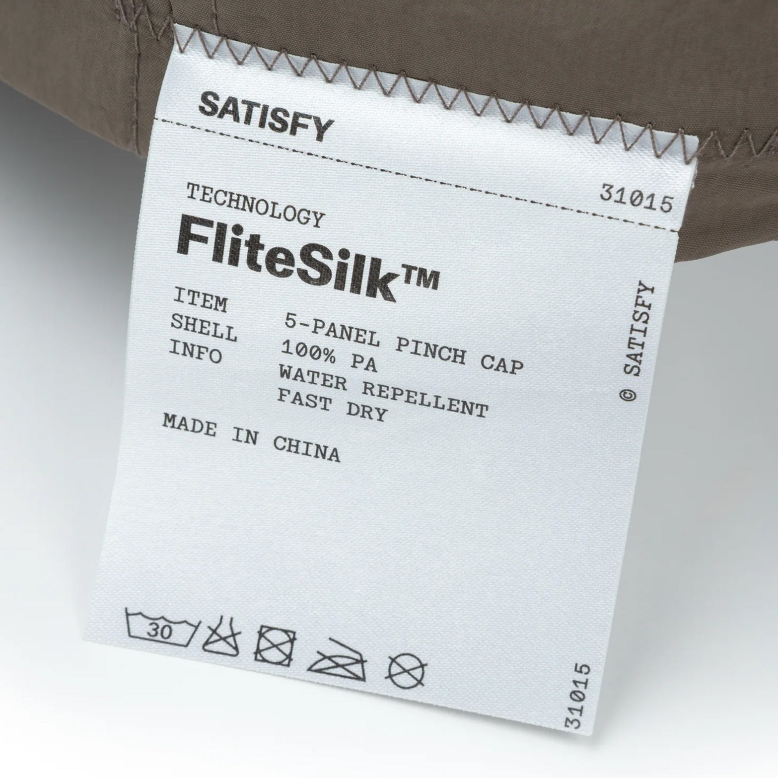 Satisfy FliteSilk™ 5 Panel Pinch Cap in Falcon Embroidery — closeup showing fully detachable exterior care label on FliteSilk™ Italian nylon fabric