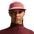 Nike Fly Unstructured Swoosh Cap Light Magenta Dusty Peach Anthracite Orange Frost front view showing 5-panel low-depth design with curved bill and Swoosh logo