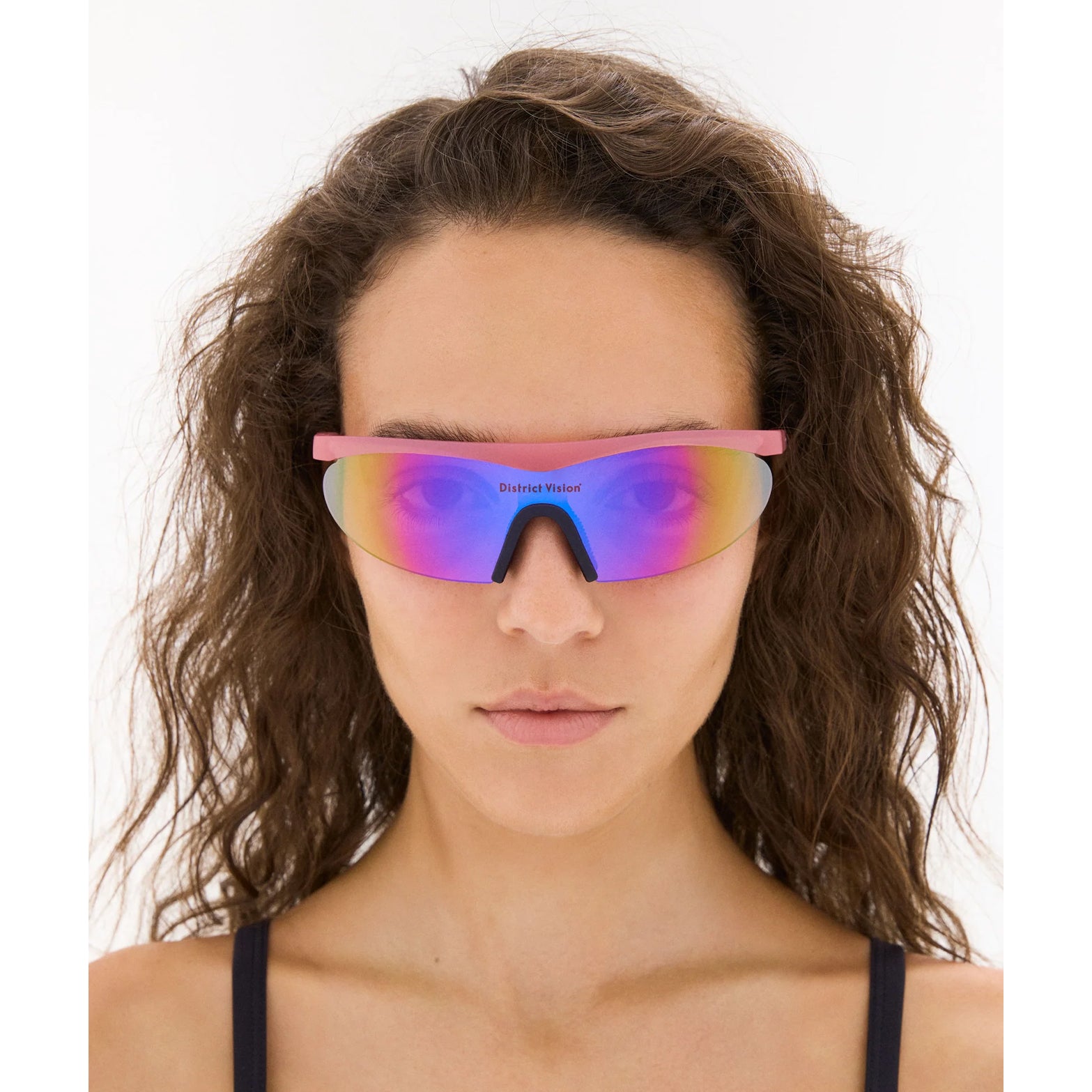 District Vision Koharu Eclipse in Desert Rose D+ Aqua Mirror — worn on female model showing six-base frame fit, desert rose colourway and D+ Aqua Mirror lens in natural light